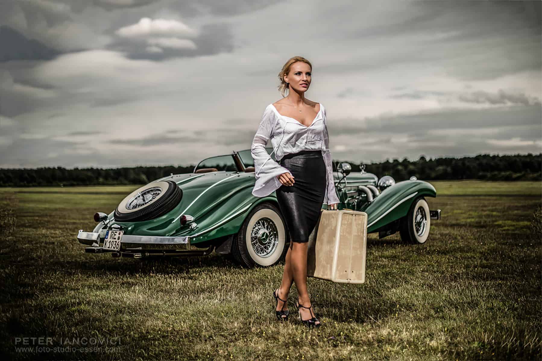 Woman and luggage beside a green vintage car